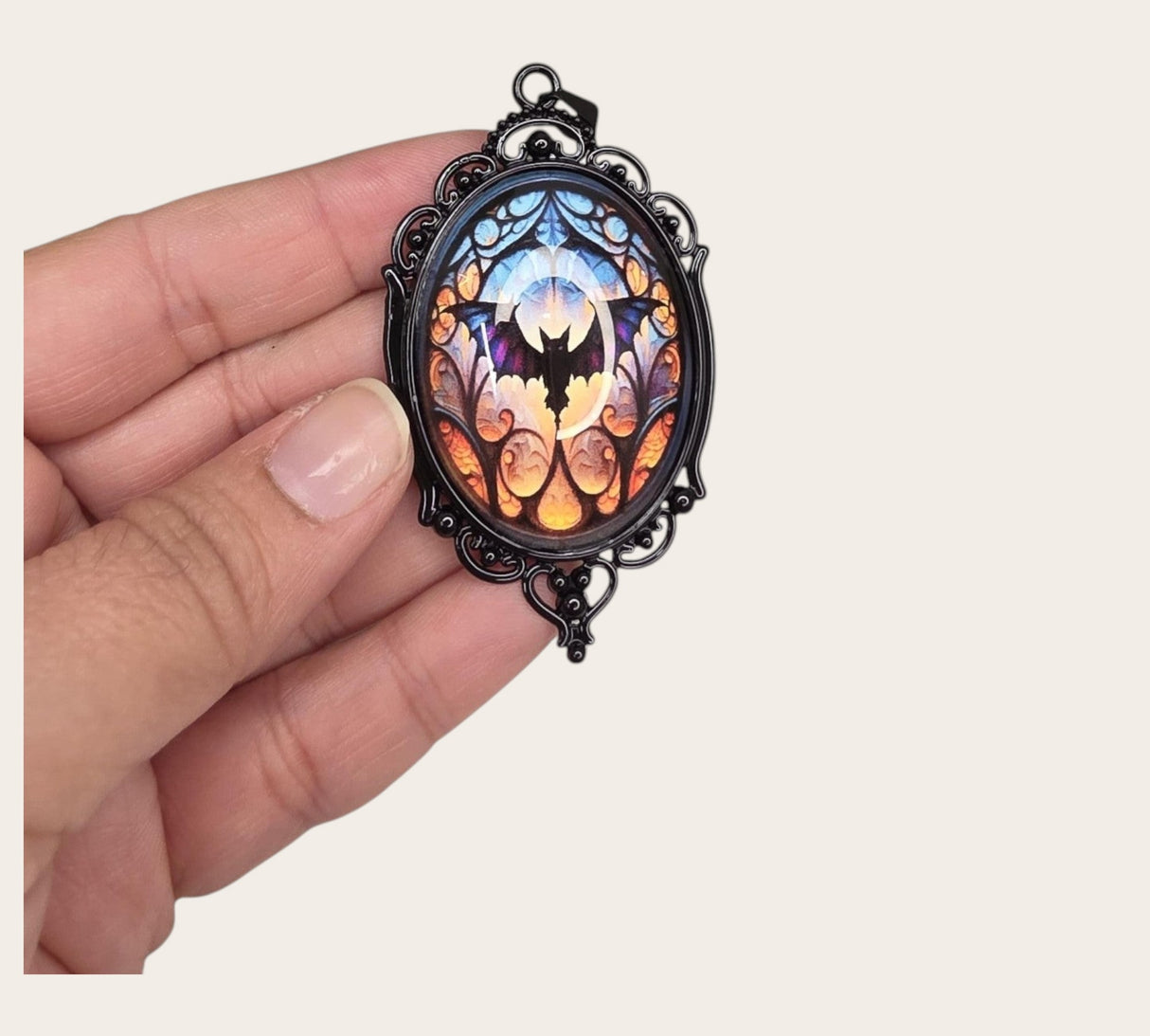 oval gothic bat pendant featuring a stained glass style cabochon in a black ornate metal frame
