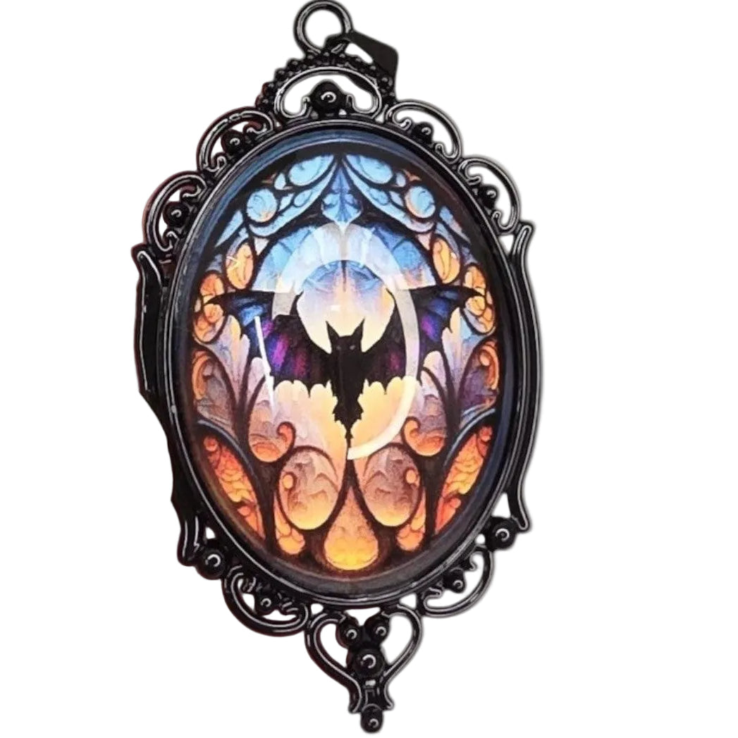 oval gothic bat pendant featuring a stained glass style cabochon in a black ornate metal frame