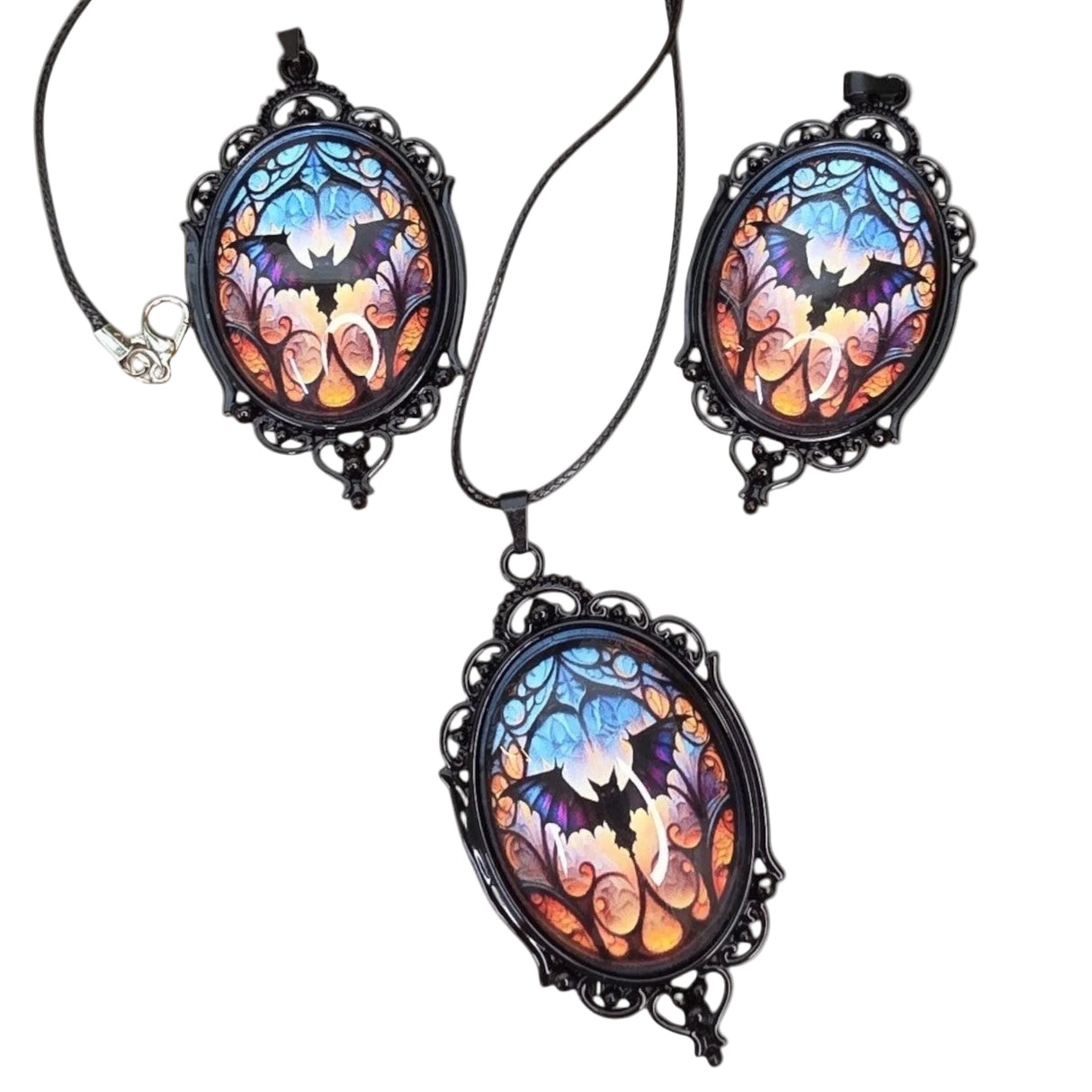 oval gothic bat pendants with stained glass style cabochons on a wooden display base.
