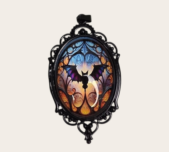 oval gothic bat pendant with a colorful glass cabochon in a black ornate frame